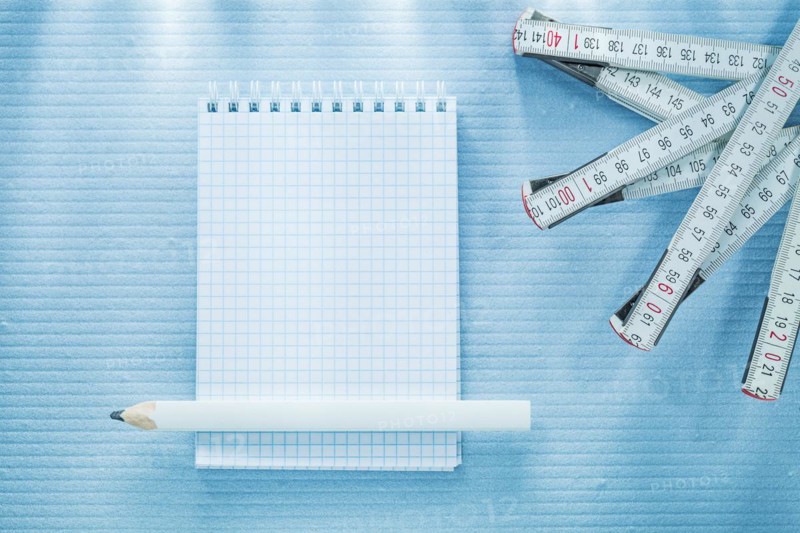 Checked notebook pencil measuring tape construction concept