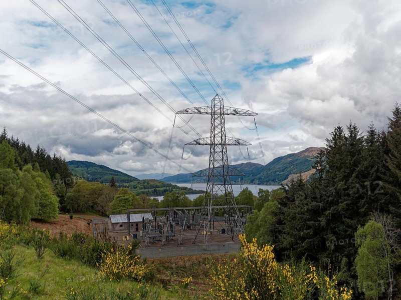 A power station in the middle of a natural landscape with electricity pylon and cloudy sky, high-voltage pylons on Loch Ness .Scotland, Great Britain