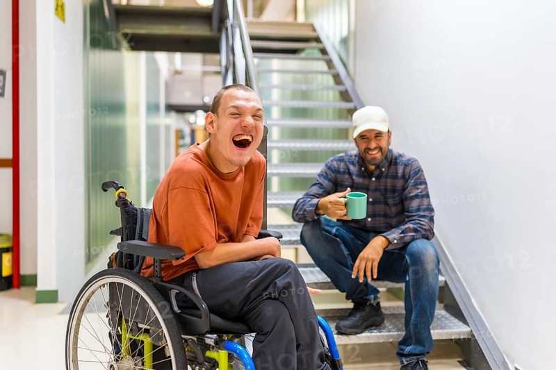 Man with cerebral palsy having fun with teamwork in coworking during a coffee break indoors