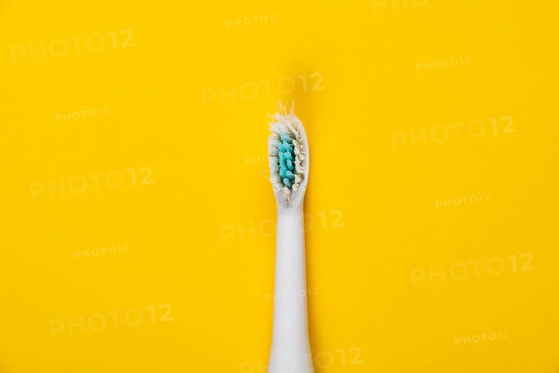 Used brush head of an electric toothbrush in front of a monochrome background