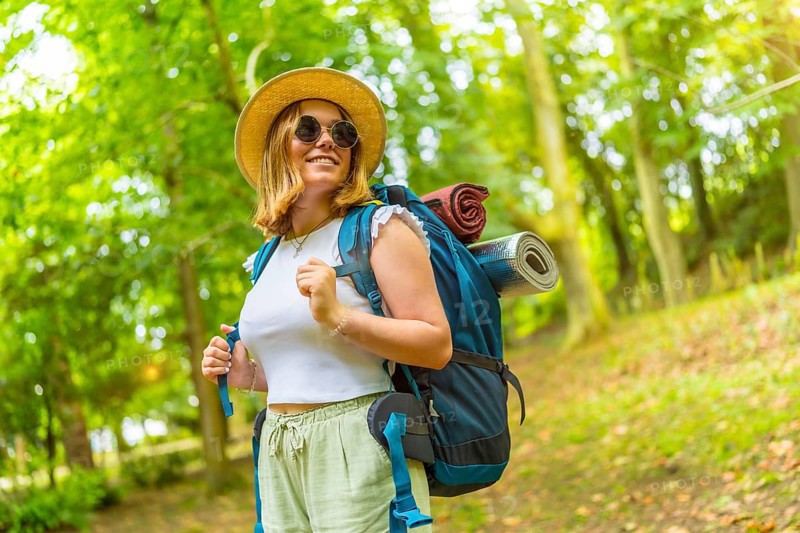 Beauty cheerful caucasian female backpacker enjoying nature while trekking in the forest