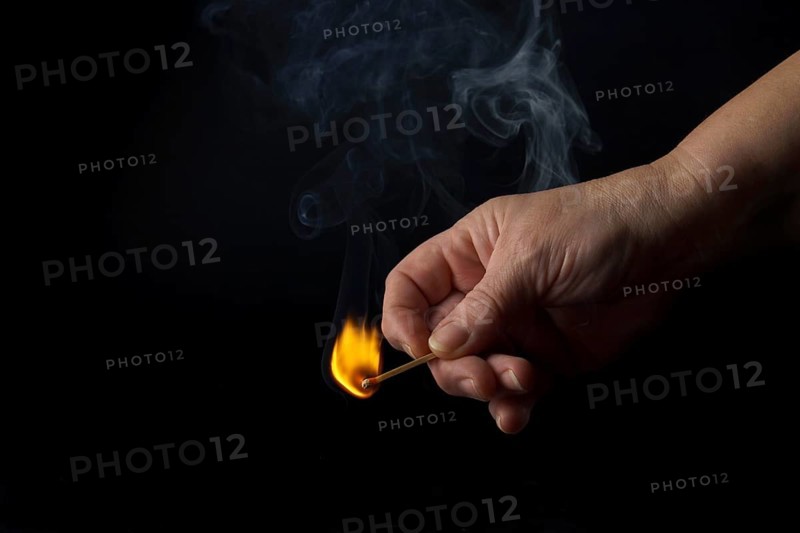 Close-up of a woman's hand lighting a match isolated on black background