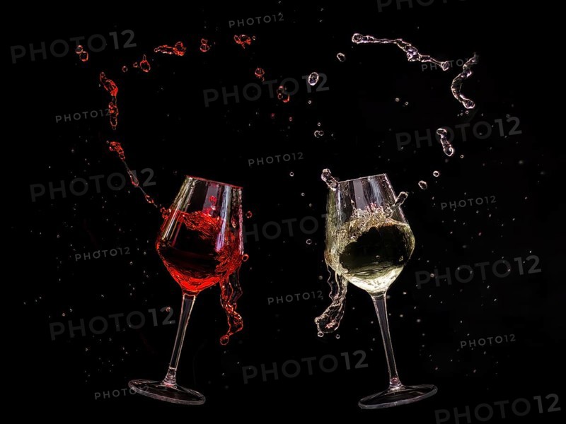 Two clinking wine glasses with red and white wine splashing out, captured in dynamic movement against a dark background