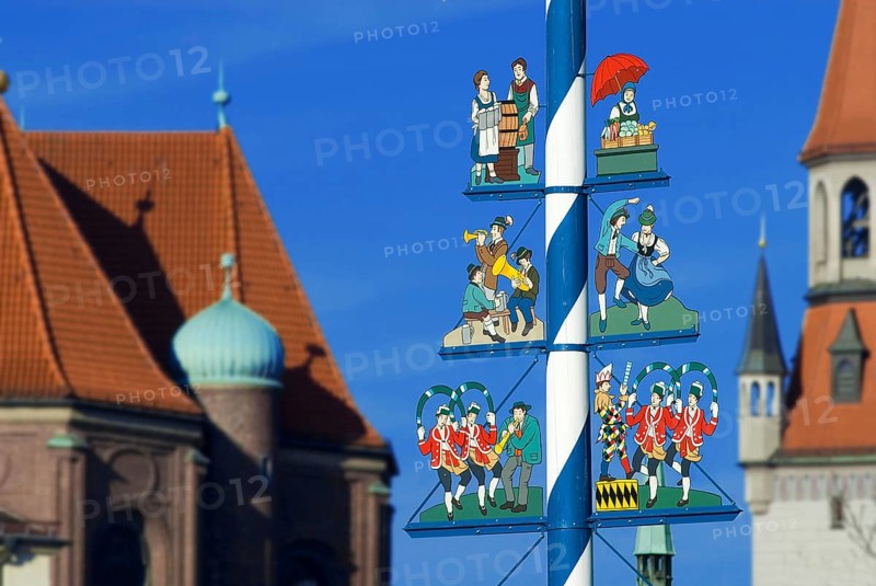 Maypole on Viktualienmarkt with musicians, dancing couple, market woman, waitress of Oktoberfest, tower of new town hall in background, Munich, Bavaria, Germany, Europe
