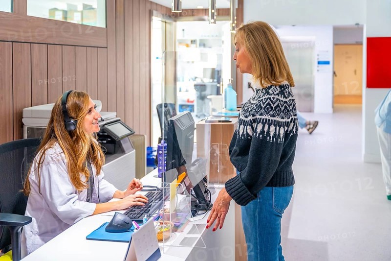 Receptionist using computer to attend a patient in the entrance of an hospital