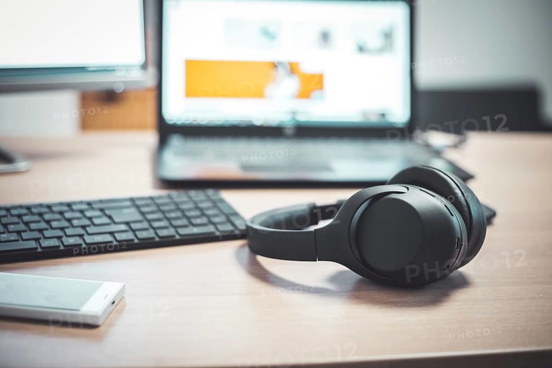 Wireless black headphones, mouse and keyboard on wooden desk