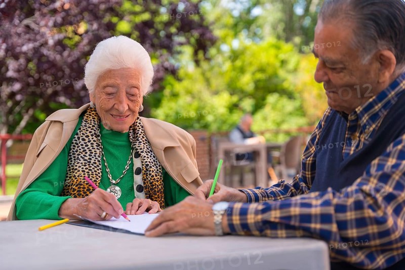 Two elderly people painting in the garden of a nursing home or retirement home