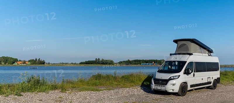 Tars, Denmark - 10 June, 2021- gray camper van parked on a gravel road at the ocean shore of Lolland Island in southern Denmark