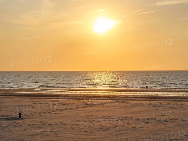 Quiet sunset on the beach with calm sea and a golden sky, oostende, belgium