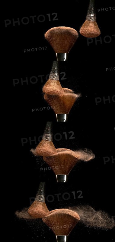 Make-up Brush spreading blush powder on black background