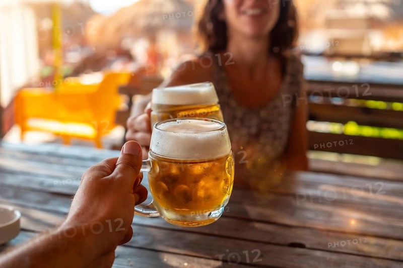 Toast of a couple on the beach in summer drinking a few beers in a celebration of friendship