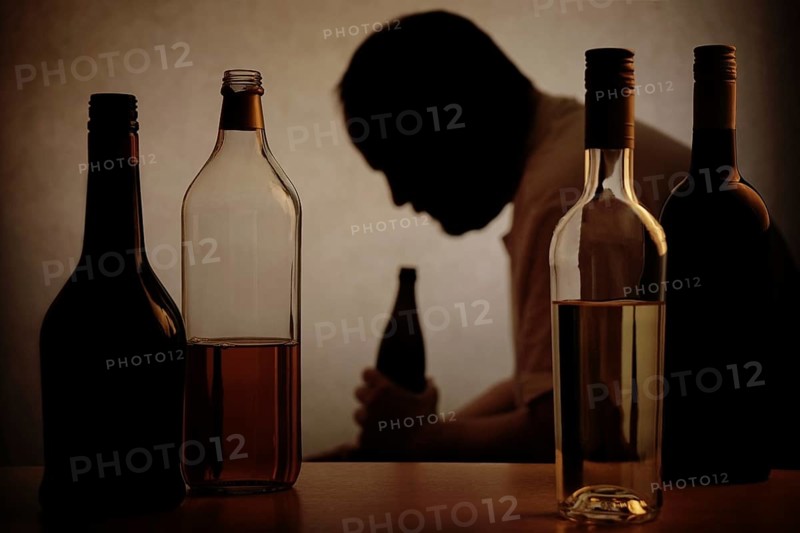 silhouette of a person drinking behind bottles of alcohol with added filter