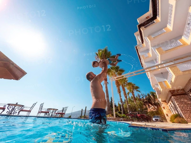 Father and son in the pool in summer playing enjoying and lifting him up on vacation