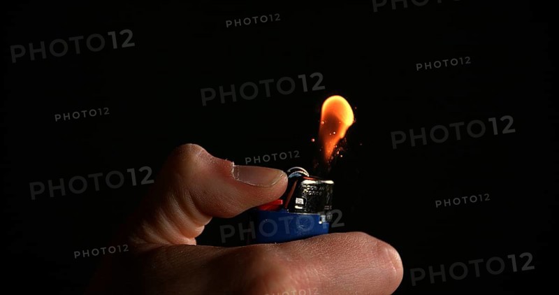 Lighter in Hand with Flame against Black background