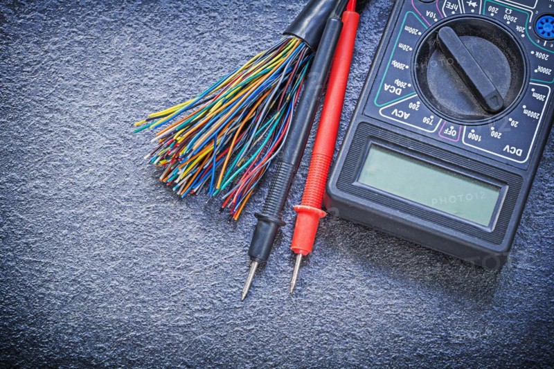 Digital multimeter electrical tester cables on black background electricity concept