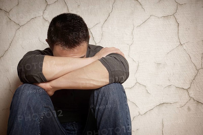 depression devastated young man hiding his face