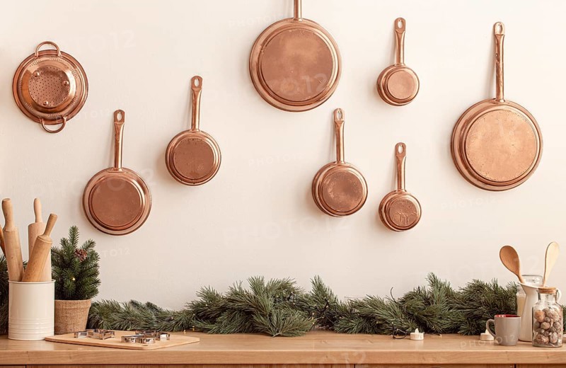 Christmas decorated kitchen counter or table in bright modern festive cozy interior with baking utensils, rolling pins, metal cookie molds, copper pans on wall, little Christmas tree, space for text