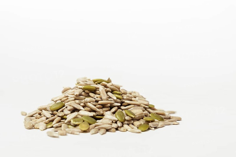 Pile of peeled pumpkin and sunflower seeds isolated on white background and copy space