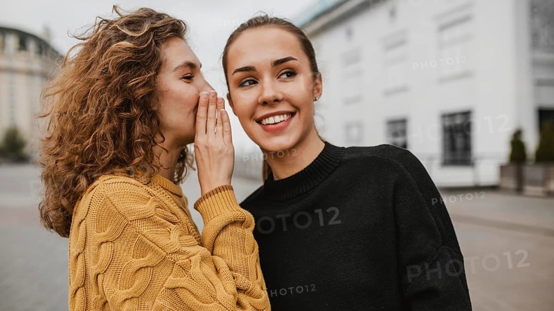Portrait teenager whispering her friends ear