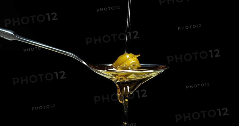 Green Olive, Olea europaea, Falling in a Spoon against Black Background