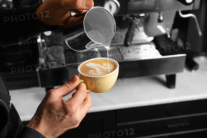 Close up hand pouring milk delicious coffee cup