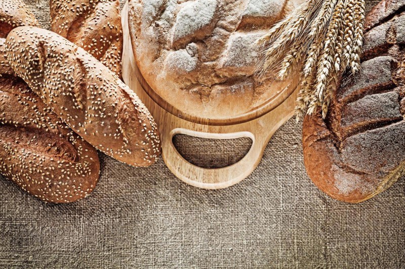 Black bread breadstick cutting board wheat ears on hessian background