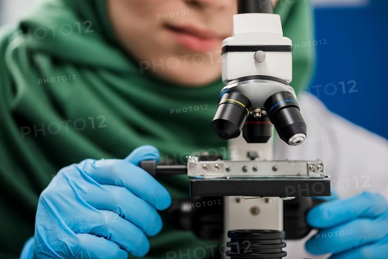 Female scientist with hijab working lab with microscope