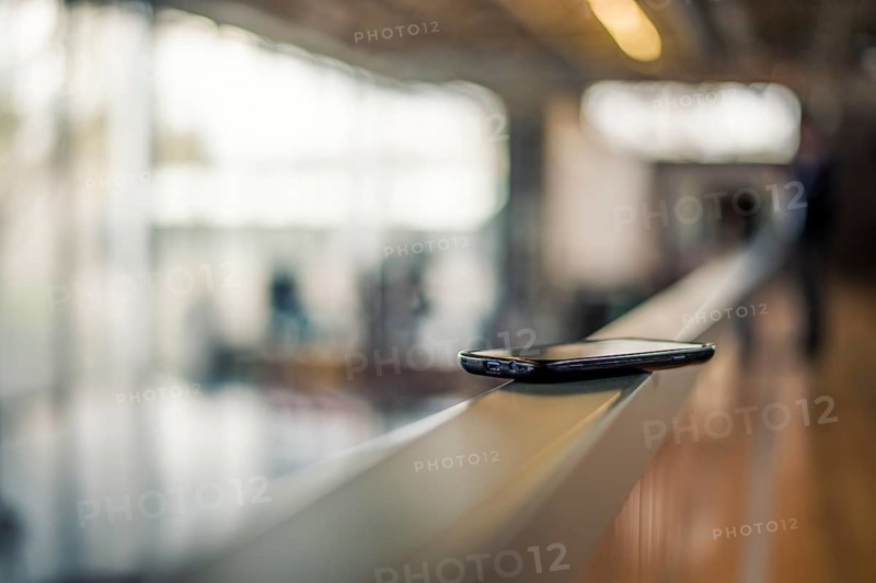A smartphone lies on a railing