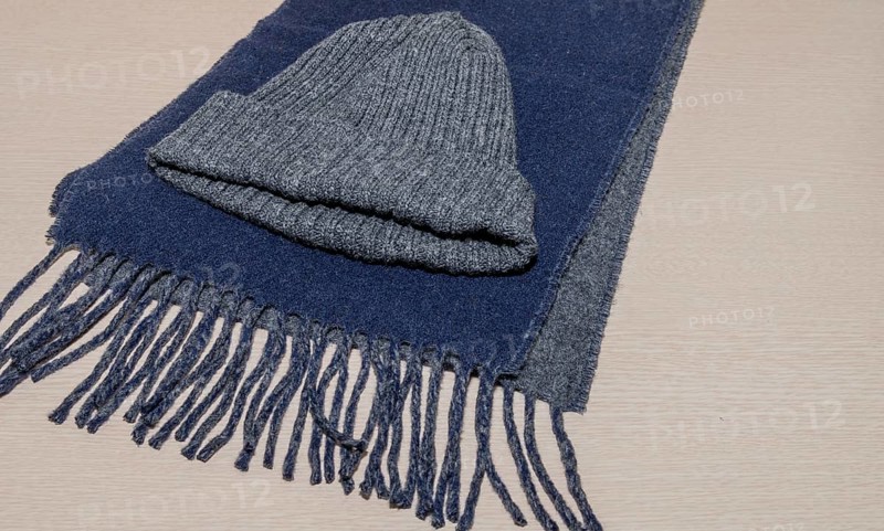 Gray knit cap laying on blue scarf on wood grain background, South Korea, South Korea, Asia