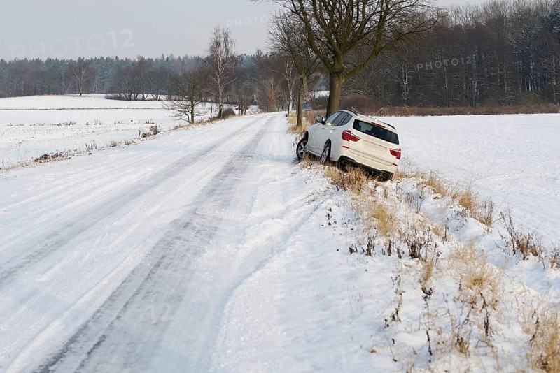 White SUV crashed in a country road kerbside due to slippery road covered in snow with skid marks
