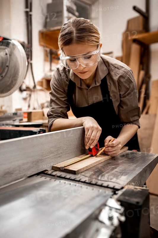 Female carpenter working studio with electric saw