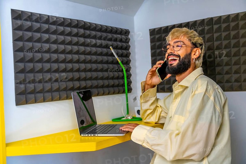 Young modern man using laptop and talking to the mobile in a coworking space