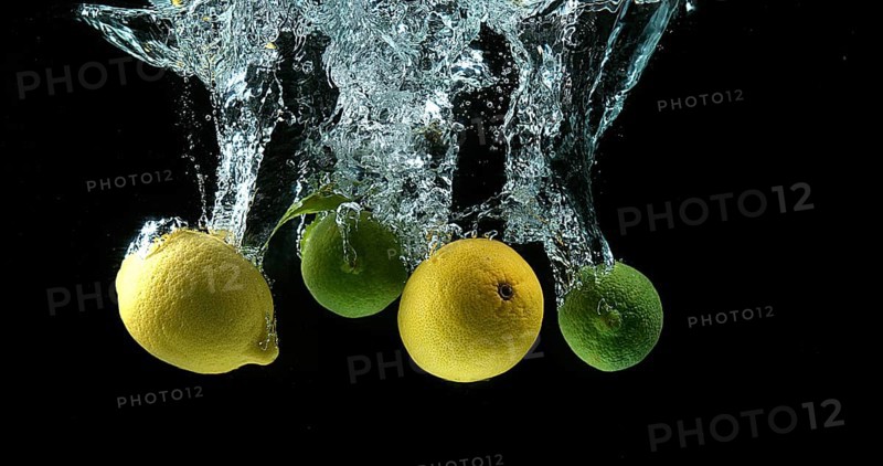 Yellow and Green Citrus, citrus limonum (Citrus aurantifolia), Fruits falling into Water against Black Background