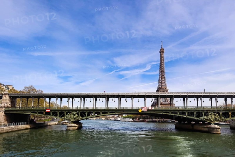 Eiffel Tower against blue sky with clouds and a bridge Pont de Bir-Hakeim (pont de Passy) over Seine River. Paris France. April 2019