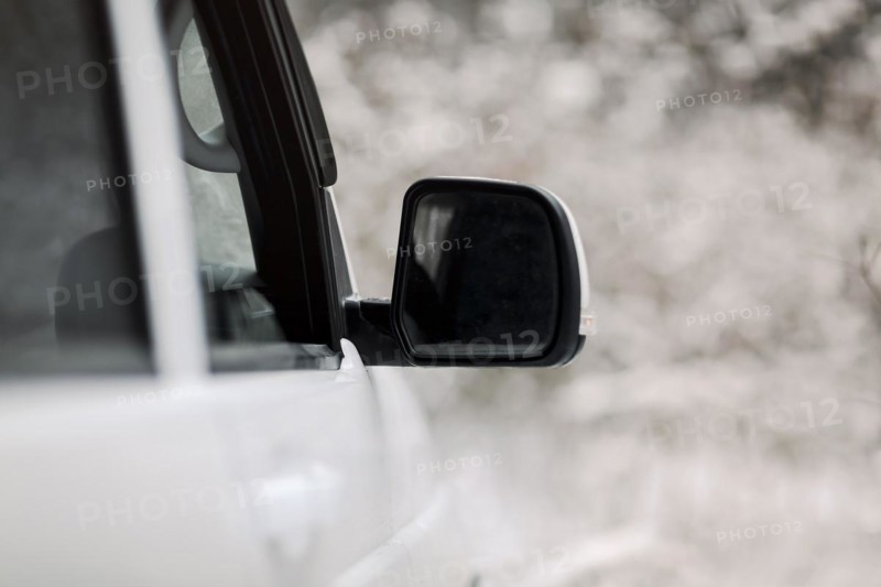 Soft focus of white vehicle with wing mirror parked in snowy countryside in winter