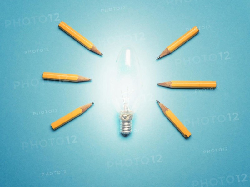 A glowing light bulb with 6 pencils as light rays, New ideas or creativity concept on blue background, business concept