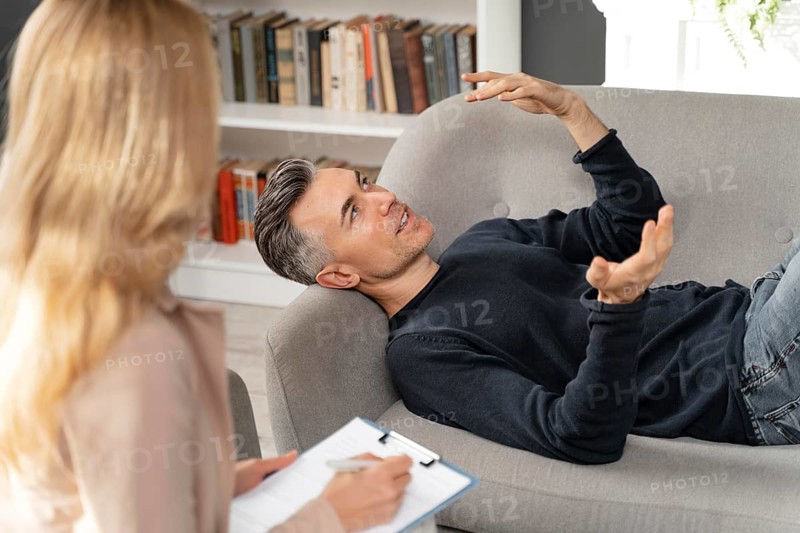 Mid shot man laying couch therapy cabinet