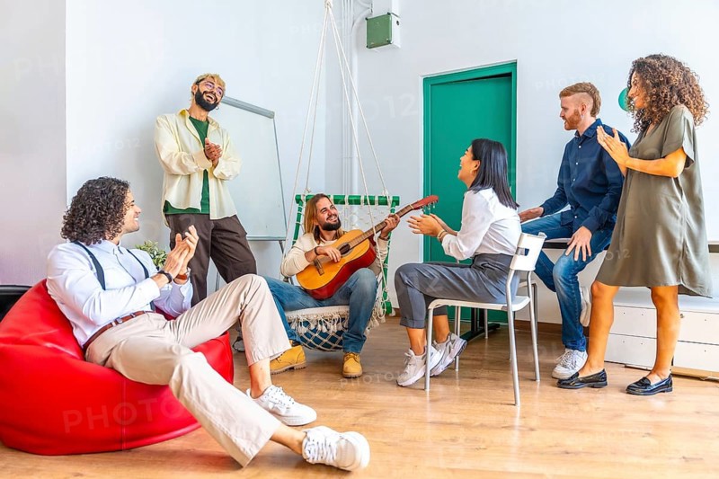 Distracted people singing and playing guitar during a break in a coworking