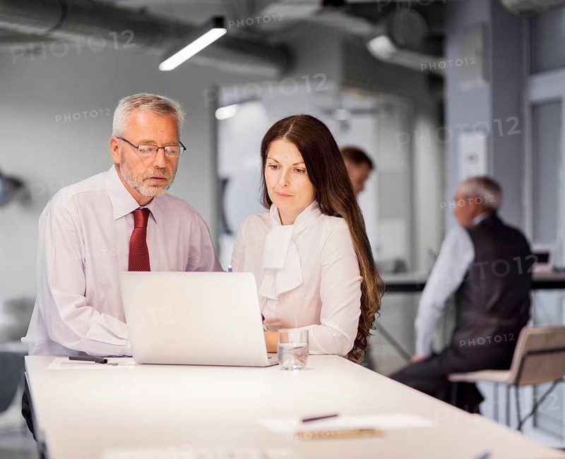 Senior businessman businesswoman looking laptop office
