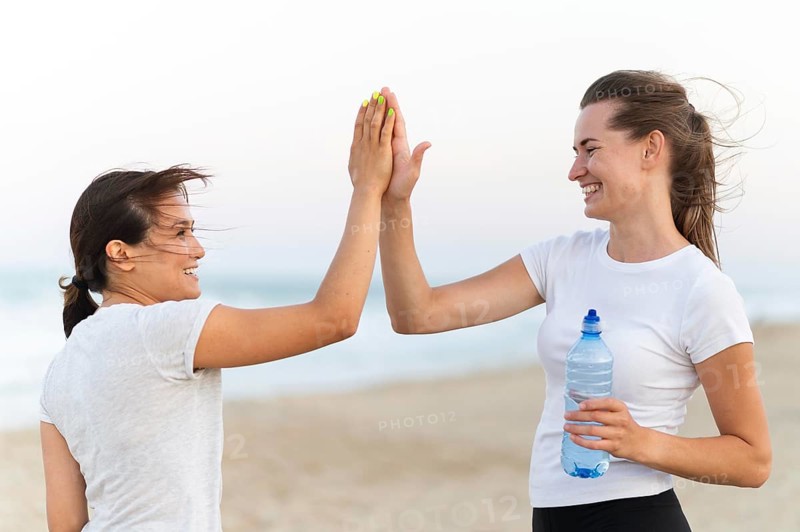 Side view two women high fiving each