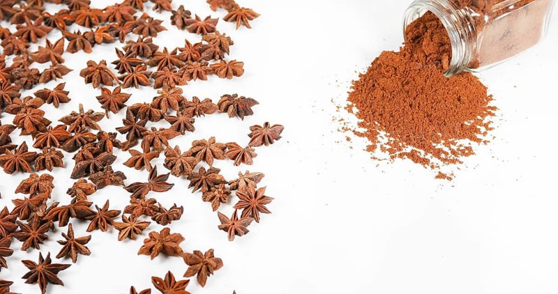 Star Anise (illicium verum), powder falling against White Background