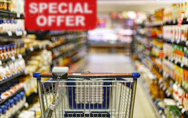 A shopping cart by a store shelf in a supermarket