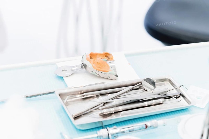 Close-up of a common stamotological instrument next to a metal form for prosthetics. Dental equipment. Dental hygiene and healthcare concept