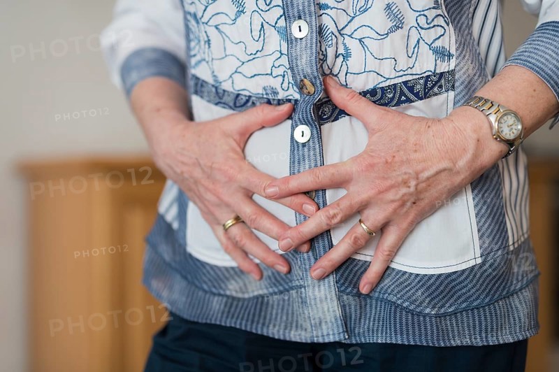 A woman's hands clasped in front of her stomach