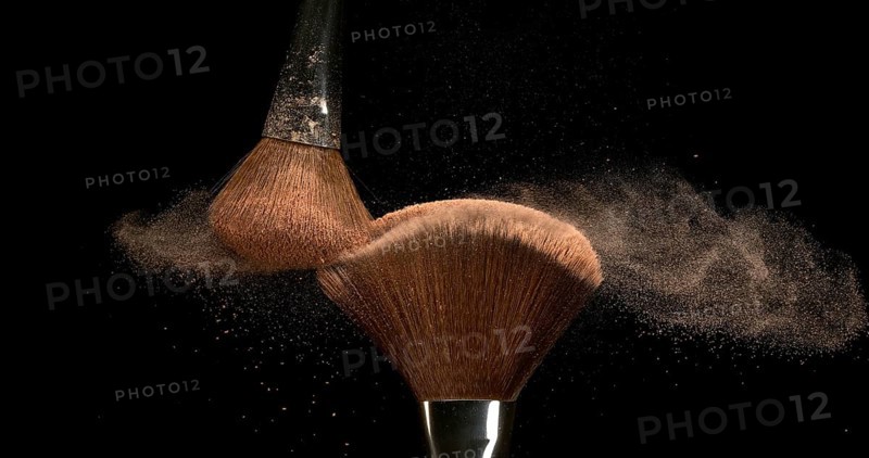 Make-up Brush spreading blush powder on black background