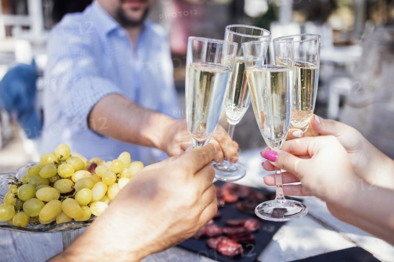 Happy people on the beach having a party, drinking and having a lot of fun in the sunset, they are wearing smart casual clothes and drink champagne