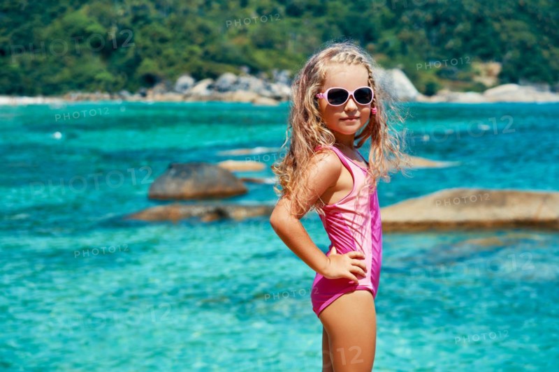 Cute little girl in sun glasses posing on beautiful tropical beach. Summer, fun and vacations concept