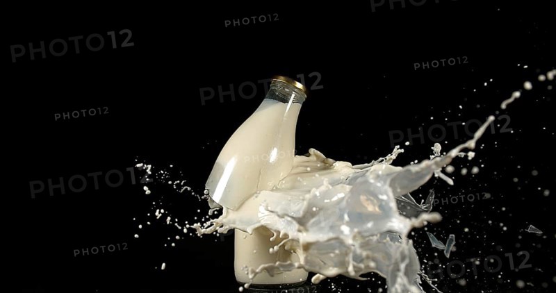 Bottle of Milk Exploding against Black Background