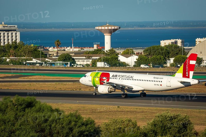 Jul 23, 2023, Lisbon, Portugal. Air Portugal or TAP airplane on runway of Humberto Delgado airport, known as Lisbon airport, on sunny day. Residential area and river Tagus in background