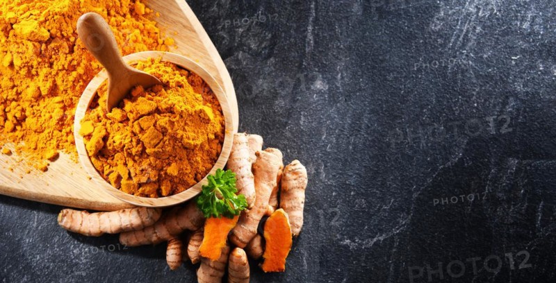 Composition with a bowl of ground turmeric and its fresh rhizome